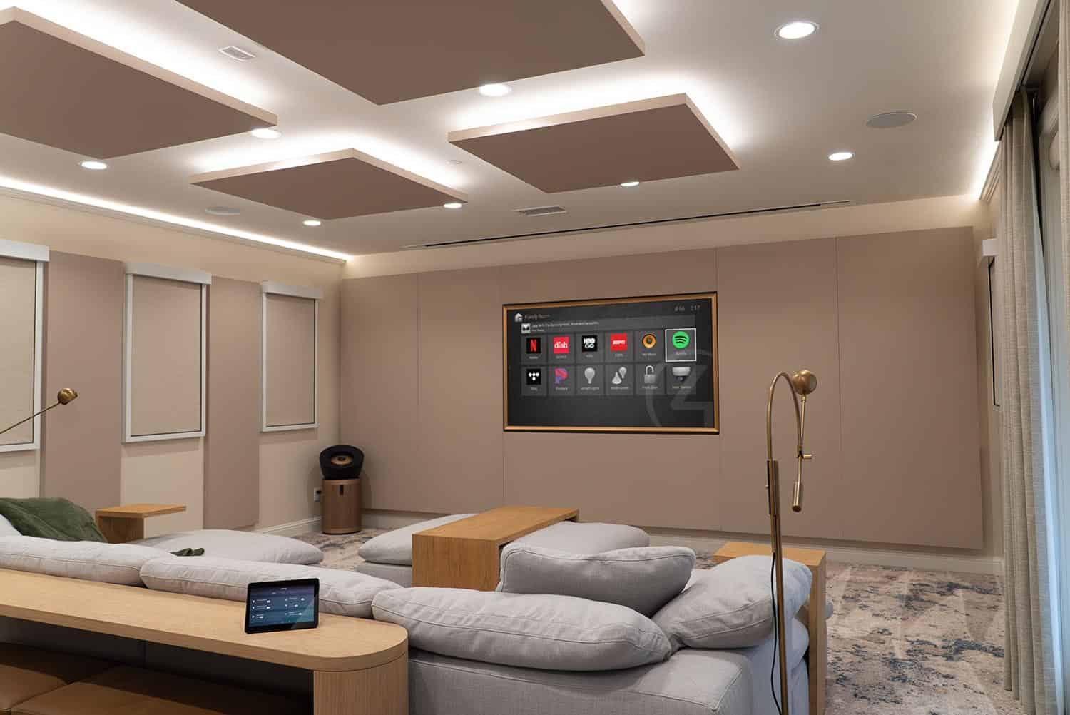 Home theater room with recessed ceiling panels, gray sectional sofa, and smart home display