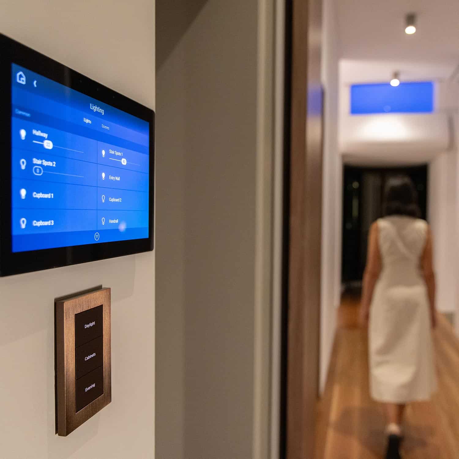 Smart home wall touch screen displaying lighting controls next to a keypad