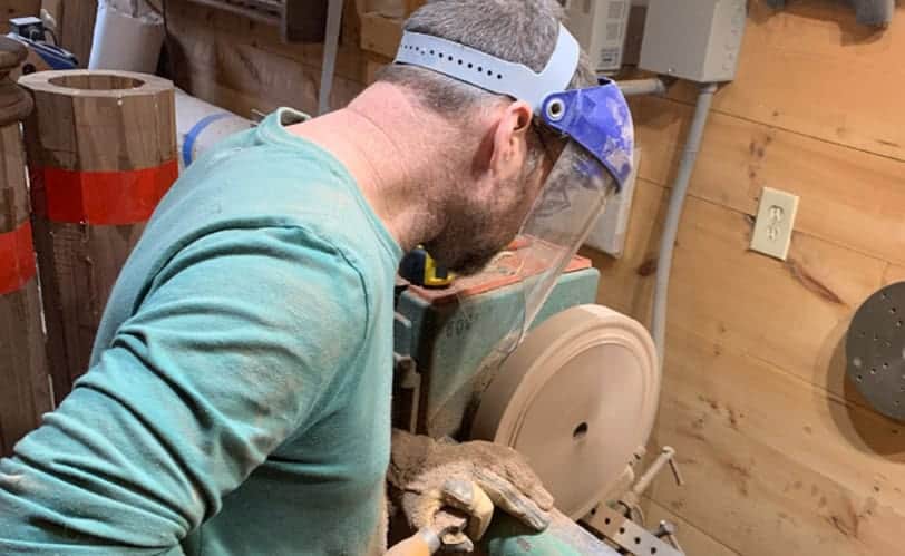 Craftsman using a woodworking machine in a workshop setting.