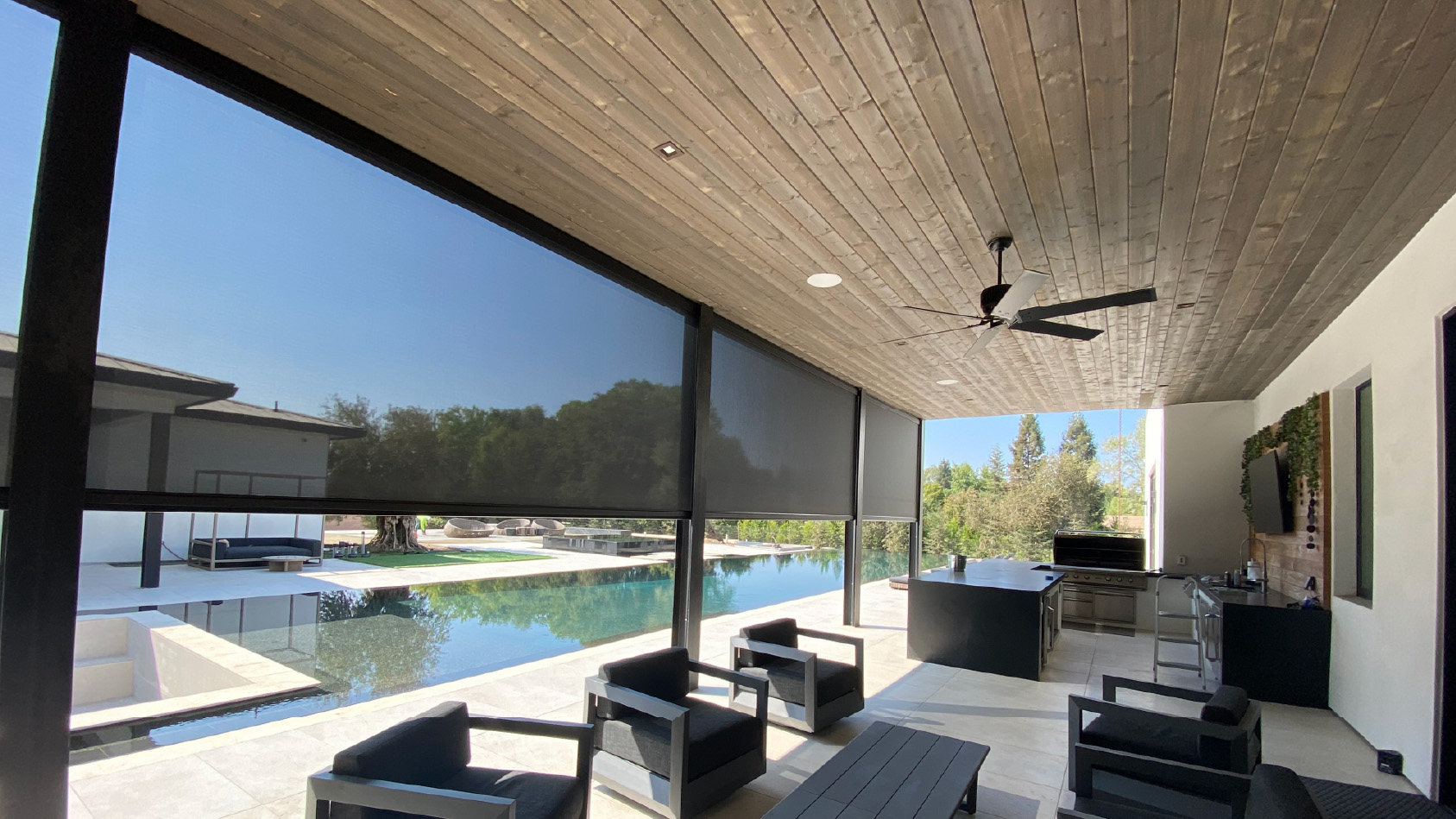 Contemporary indoor-outdoor lounge with pool view and ceiling fan.