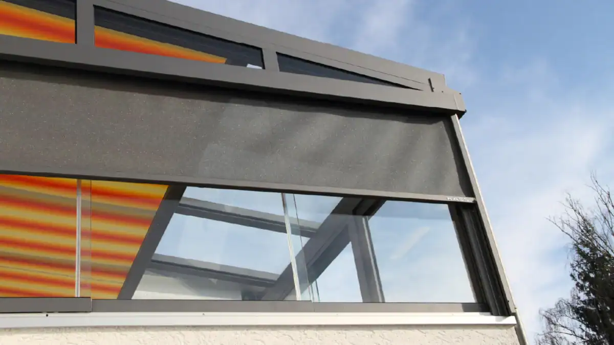 Modern commercial glass structure with metal framing and orange accents.