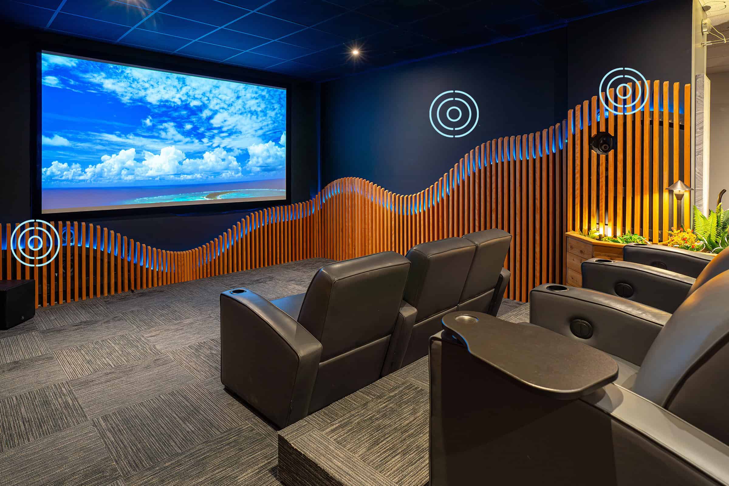 Home theater room with large screen, leather recliners, and modern decor.