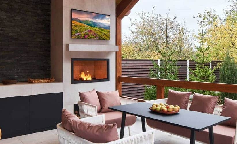 Modern outdoor patio with fireplace, TV, and seating area by Atlantic AV.