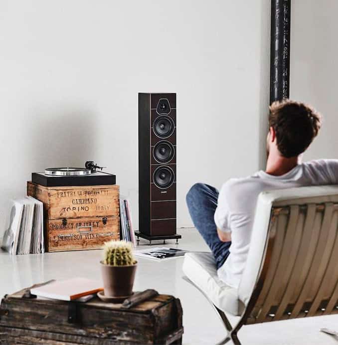 Man relaxing with high-end audio speakers in modern living room.